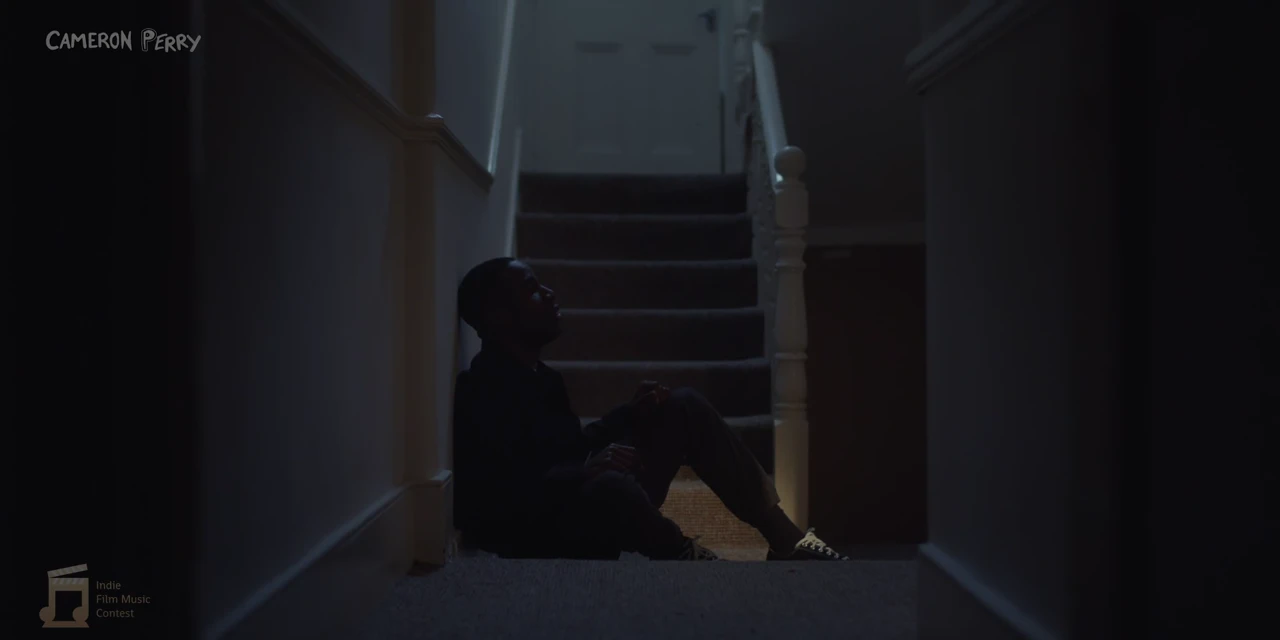 Matty sitting alone on the floor of the dark hallway at the foot of the stairs